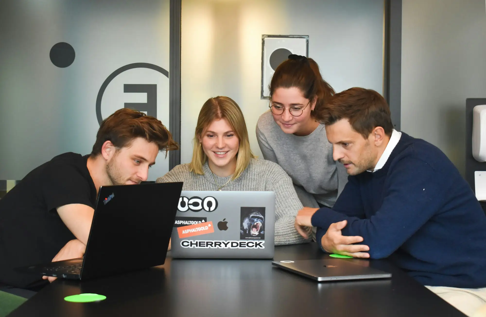Three people discuss a project at a laptop